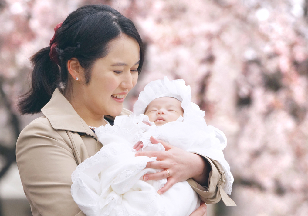 桜の前でママが赤ちゃんを抱っこしている写真