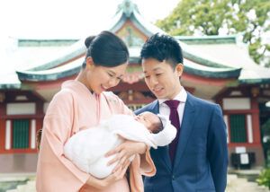 お宮参り出張撮影で品川神社の本殿前で赤ちゃんを抱っこするママとパパの写真
