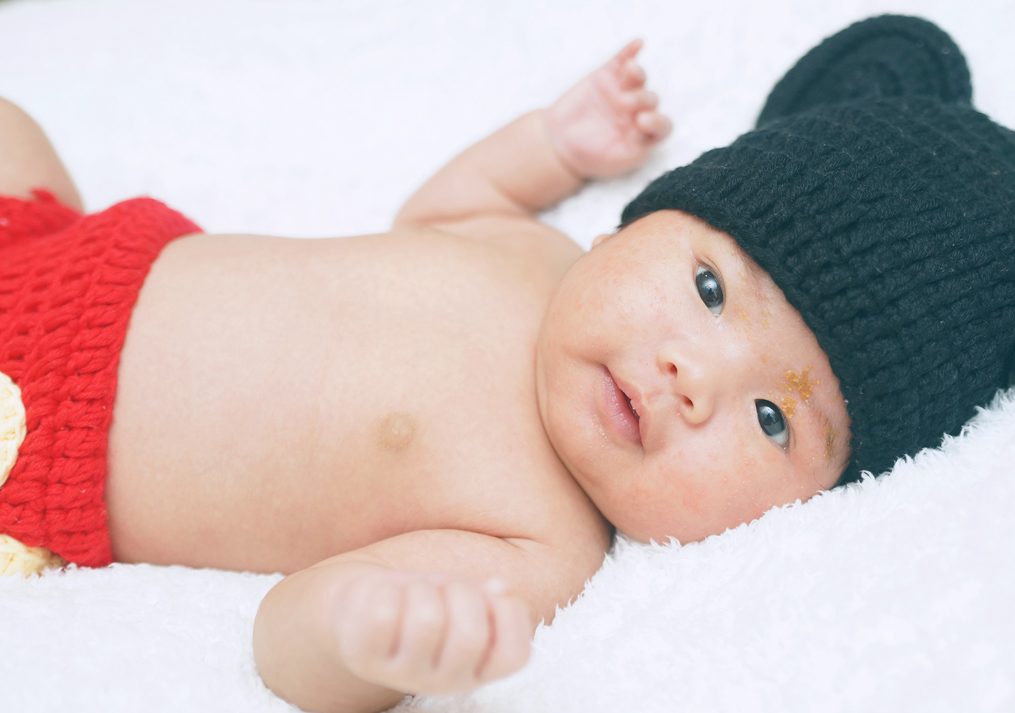ニューボーンフォトで黒い帽子を被った赤ちゃん
