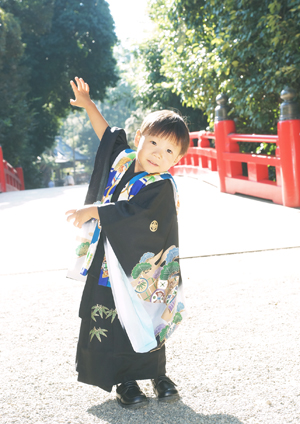 大宮氷川神社の赤い橋の上でポーズをする男の子