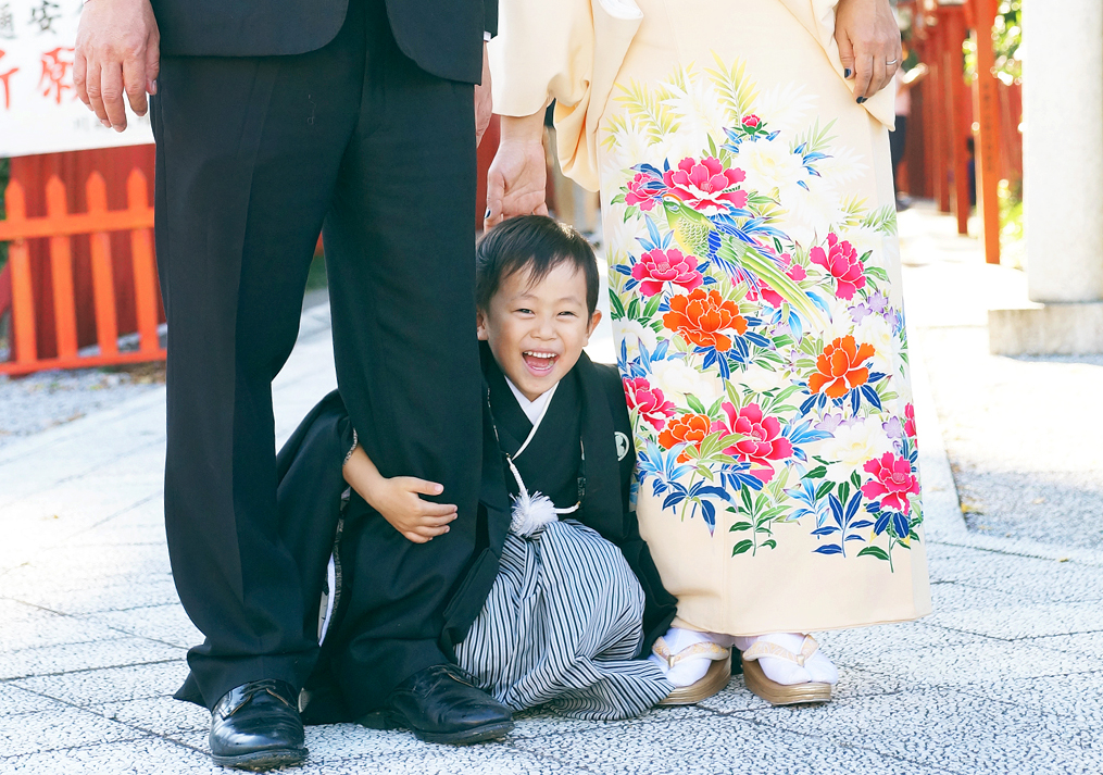 パパとママの足の間から顔を覗かせる男の子