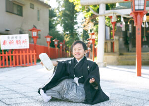 七五三出張撮影で埼玉県川越八幡宮の参道で草履を脱いで座り込む男の子の写真