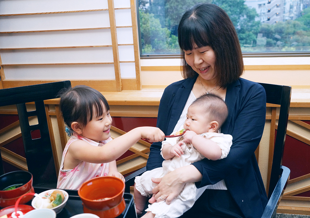 赤ちゃんに食べ物をあげようとするお姉ちゃん