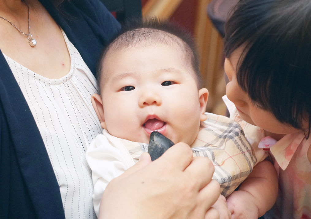 歯固めの石を舐める赤ちゃん