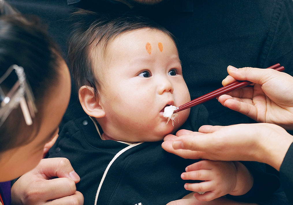 お食い初めのお新香を食べようとする赤ちゃん