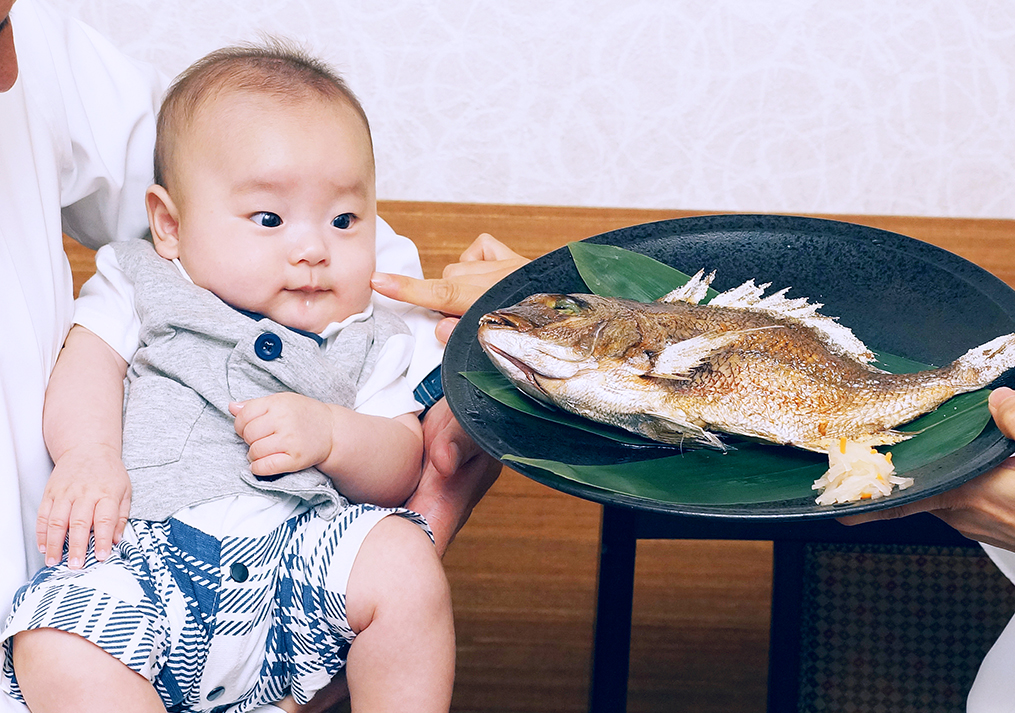 お食い初めの大きな鯛を見てびっくりする赤ちゃん