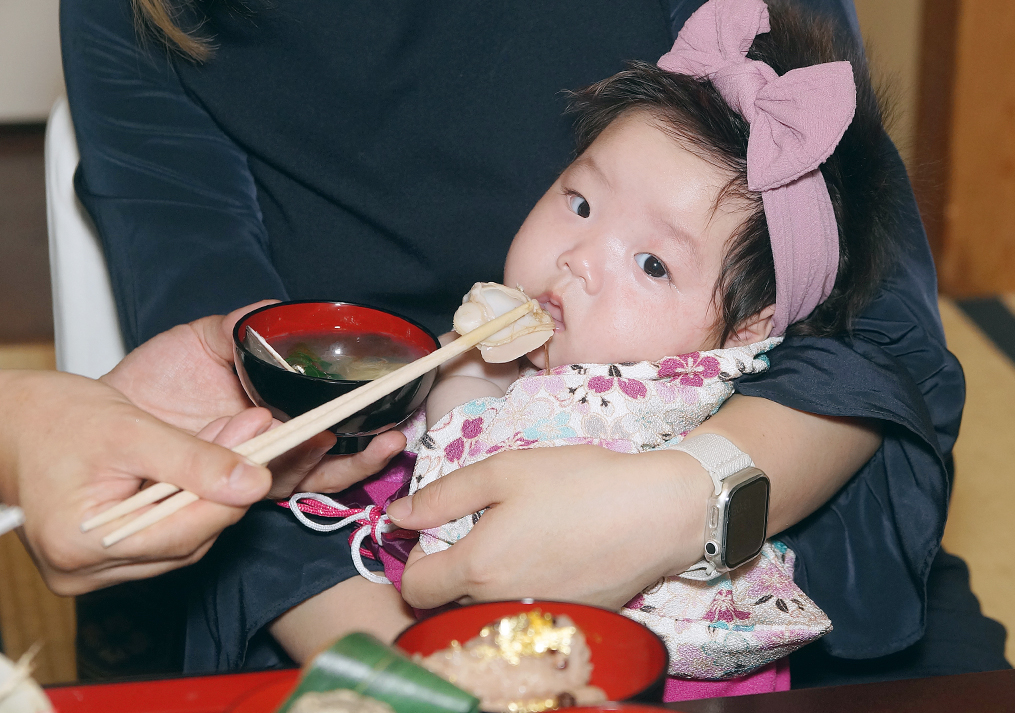 赤ちゃんの口元に寄せられるハマグリ