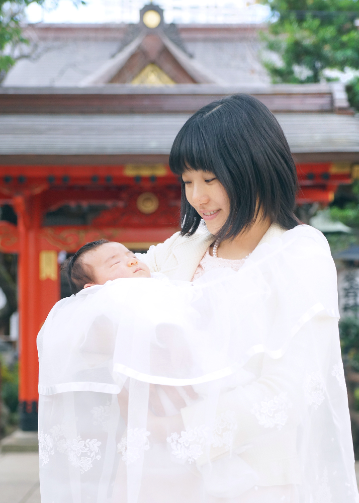 白い祝い着（産着）を掛けて赤ちゃんを抱っこするママ