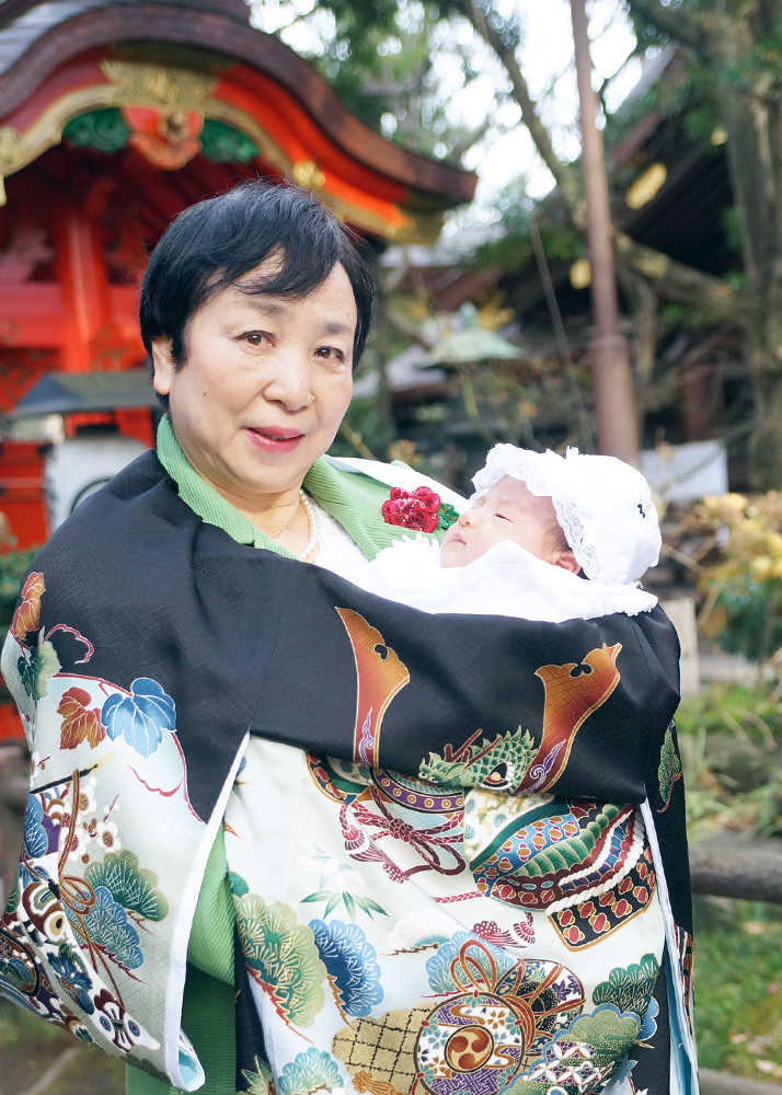 黒い祝い着（産着）を掛けて赤ちゃんを抱っこする祖母様