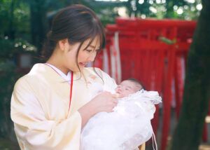 大宮氷川神社の赤い鳥居の前でお宮参りの赤ちゃんを抱っこする着物コーデのママ