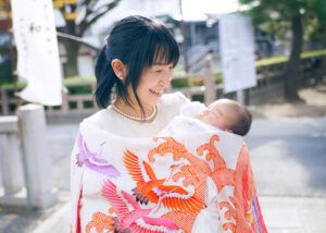 埼玉県草加神社でのお宮参り出張撮影でオレンジ色の祝い着をかけるママ