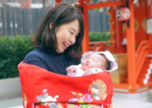水天宮でお宮参りで赤い祝い着を掛けたママ