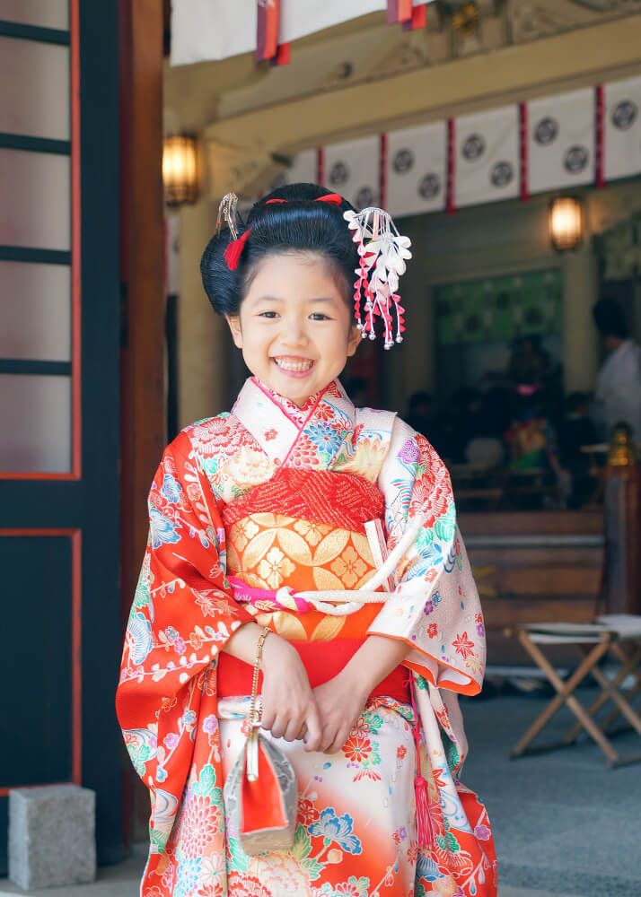 谷原氷川神社の本殿前で千歳飴を持ってポーズをとる七五三の女の子