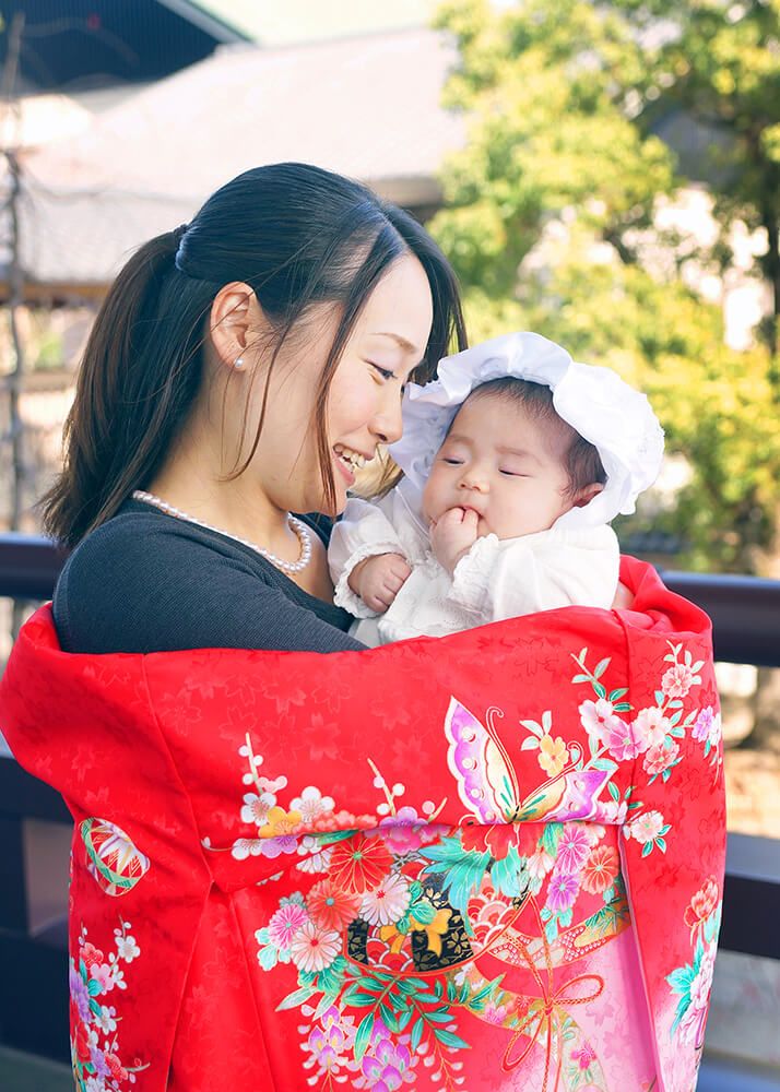 西新井大師でお宮参り出張撮影で赤ちゃんを抱っこするママの写真