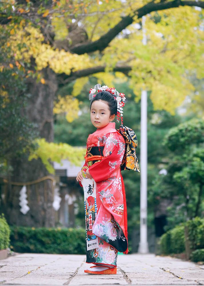 松戸神社の銀杏の木の下でポーズをとる七五三の女の子