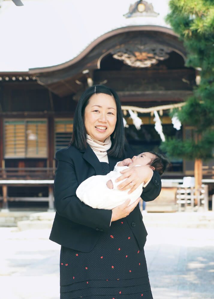 葛飾八幡宮の本殿前でお宮参りの赤ちゃんを抱っこするママ