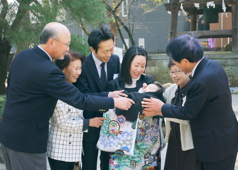 葛飾八幡宮の境内でお宮参りの赤ちゃんを囲む祖父母