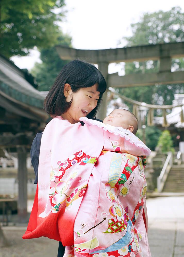 意富比神社(船橋大神宮)の鳥居前でお宮参りの祝い着をかけたママ