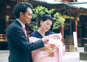 根津神社の本殿前でお宮参りの赤ちゃんを抱っこするママの写真
