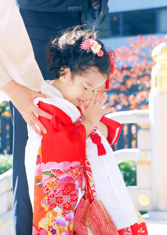 水天宮の拝殿の前でお参りをする赤い着物の3歳女の子