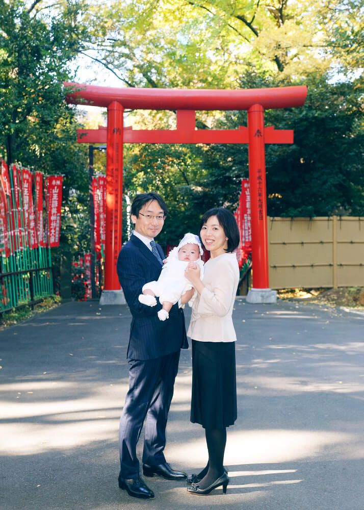 赤坂日枝神社の千本鳥居の前でお宮参りの赤ちゃんを抱っこするママとパパ