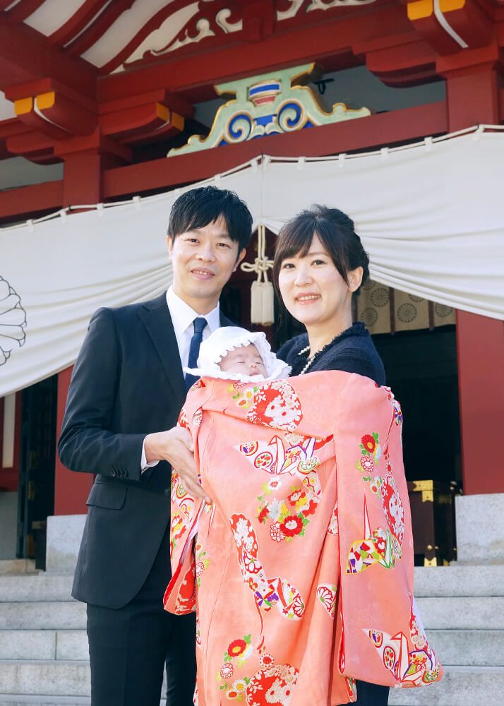 赤坂日枝神社でのお宮参り出張撮影でオレンジ色の祝い着をかけて赤ちゃんを抱っこするママとパパ