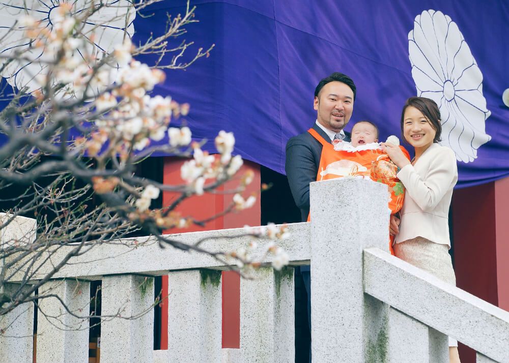 赤坂日枝神社でのお宮参り出張撮影でオレンジ色の祝い着をかけて赤ちゃんを抱っこするパパ