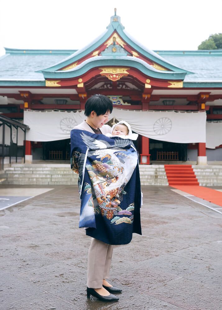 赤坂日枝神社でのお宮参り出張撮影で青い祝い着をかけて赤ちゃんを抱っこするママ