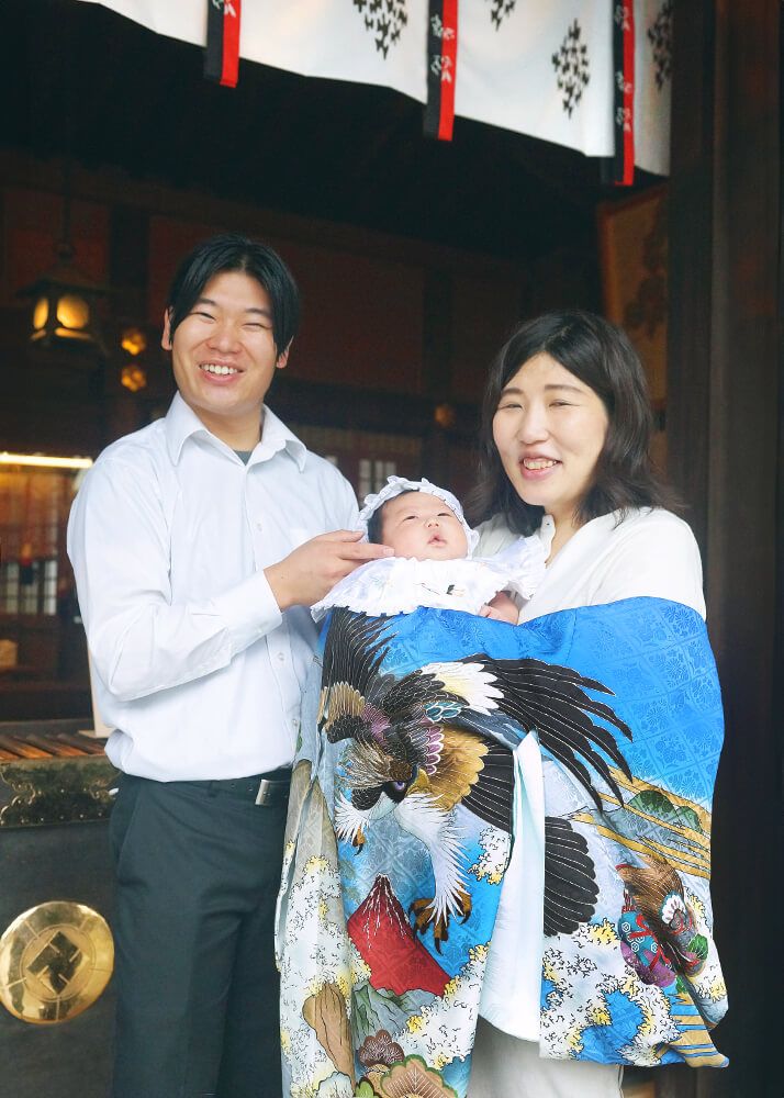 松陰神社|お宮参り・七五三・お食い初め写真 17 お宮参り出張撮影で世田谷区松陰神社の本殿の前で赤ちゃんを抱っこするママとパパの写真
