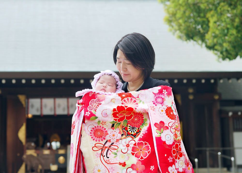 松陰神社|お宮参り・七五三・お食い初め写真 14 お宮参り出張撮影で世田谷区松陰神社の本殿の前で赤ちゃんを抱っこするママの写真