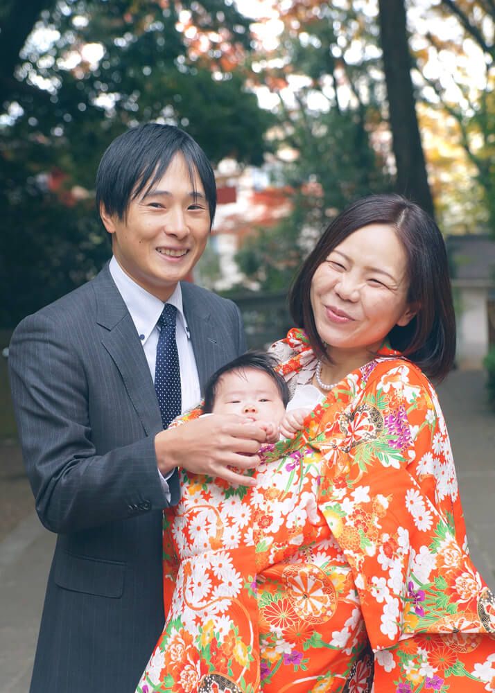 お宮参り出張撮影で世田谷八幡宮の境内で赤ちゃんを抱っこするママとパパ