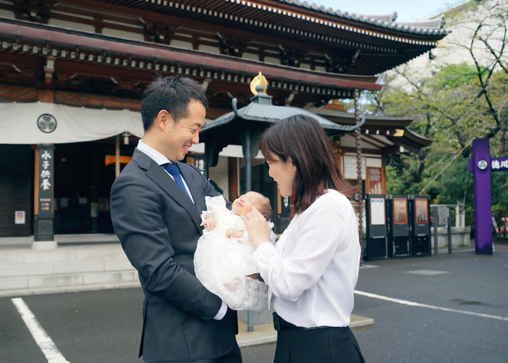 お宮参りの出張撮影で増上寺の安国殿の前で赤ちゃんを抱っこするパパとママ