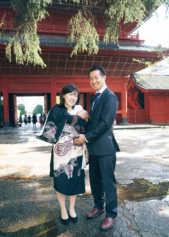 お宮参りの出張撮影で港区増上寺の三解脱門の前で赤ちゃんを抱っこするパパとママ
