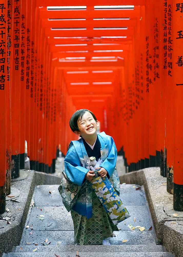 着物で揃えた家族の七五三写真|赤坂日枝神社 10 赤坂日枝神社での七五三出張撮影で赤い鳥居の中ではしゃぐ男の子の写真