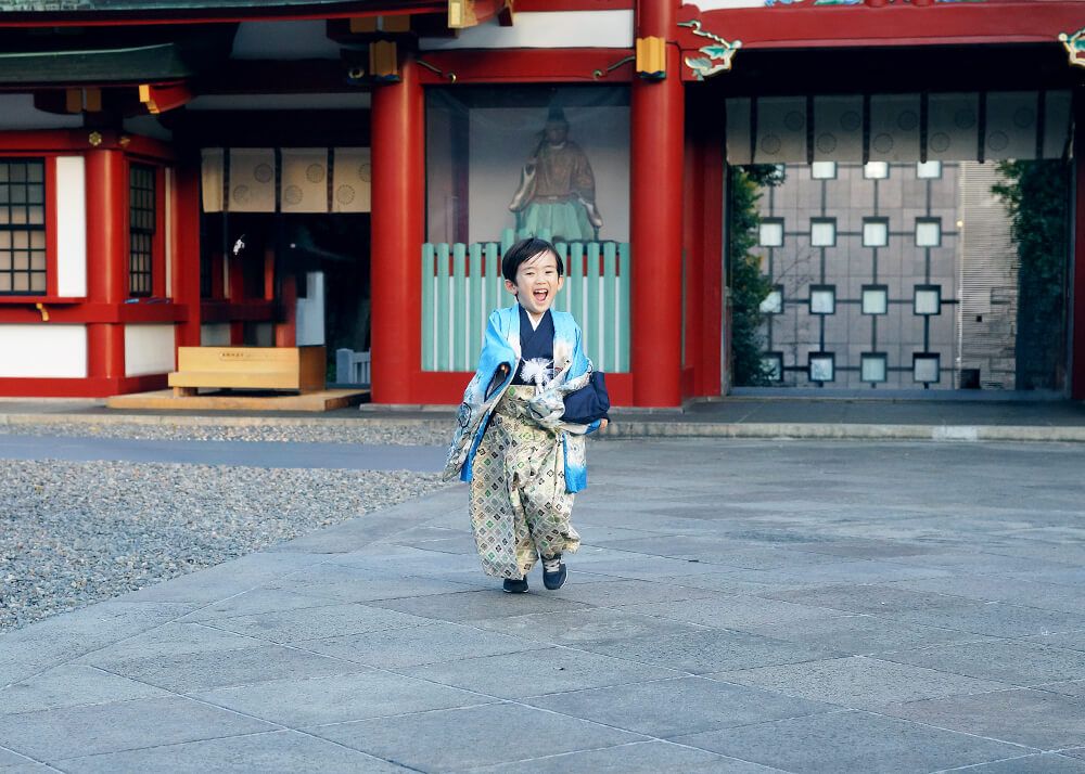 鼻の穴に指が入っているお姉ちゃん 赤坂日枝神社での七五三出張撮影で境内を走る男の子の写真