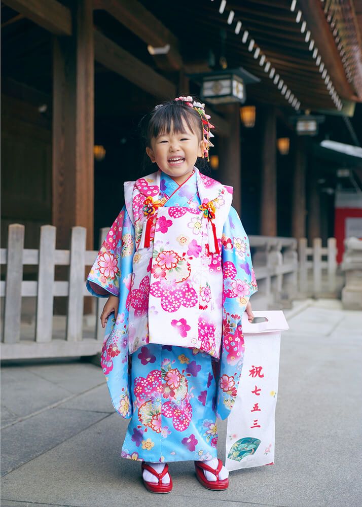 七五三出張撮影で人見知りの3歳女の子が千歳飴を持ってポーズをとる写真