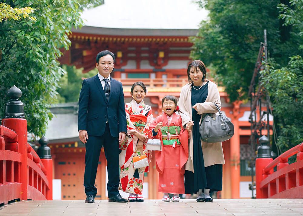 鼻の穴に指が入っているお姉ちゃん 七五三ロケーションフォトで大宮氷川神社の赤い橋の上で家族の写真