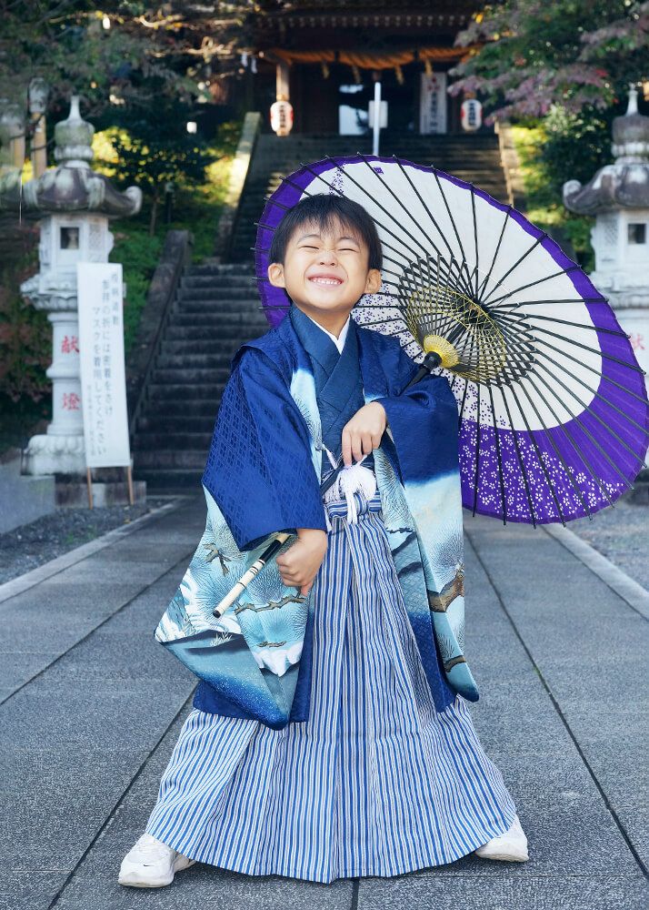 七五三出張撮影で中氷川神社の参道で和傘を持ってポーズをとる男の子の写真