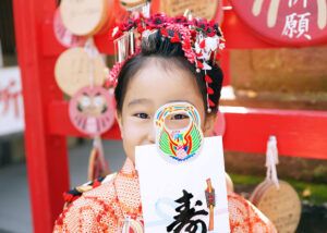 川口鎮守氷川神社での七五三出張撮影で7歳女の子が千歳飴を持って笑顔を見せる写真