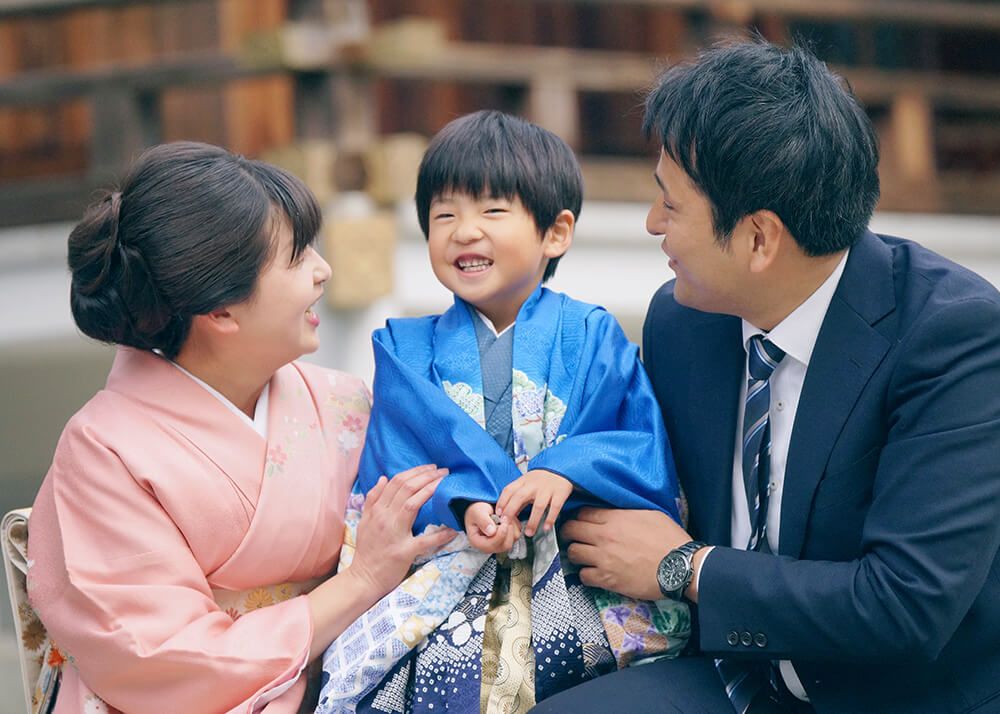 七五三出張撮影で中野沼袋氷川神社の境内で青い着物を着た男の子と家族の写真