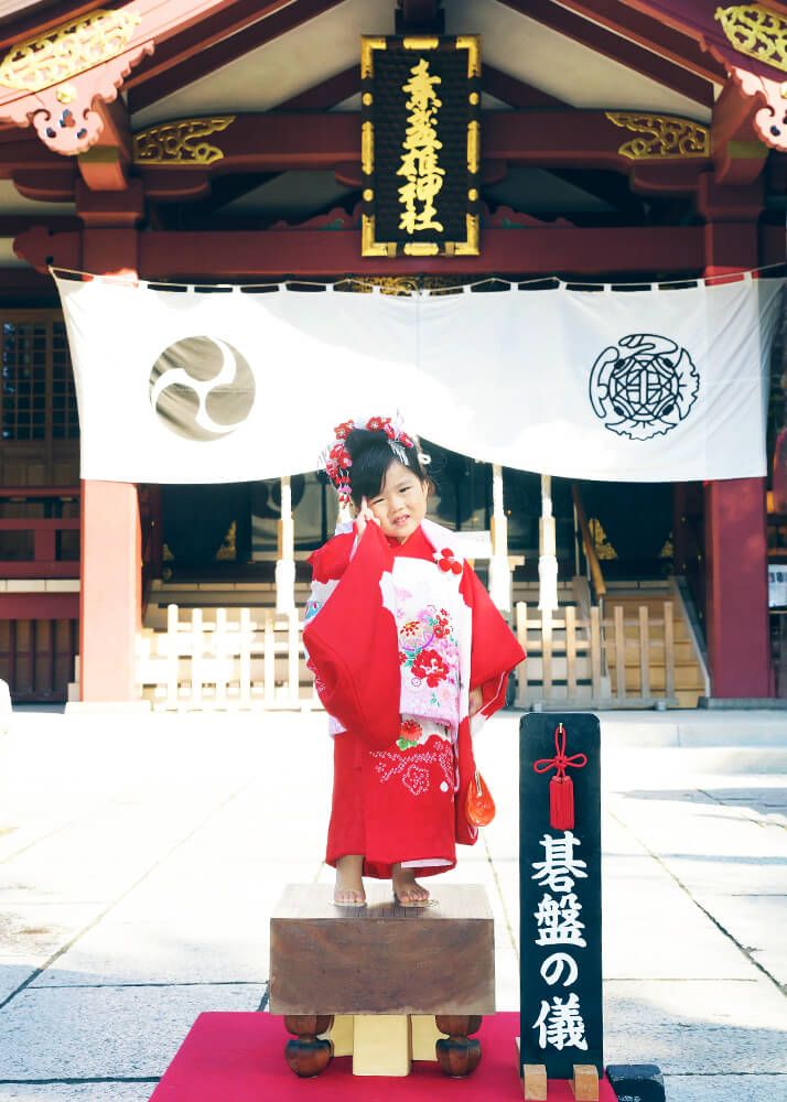 素盞嗚神社|お宮参り・七五三・お食い初め写真 13 七五三出張撮影で素盞嗚(スサノオ)神社の拝殿前で碁盤に立つ女の子の写真