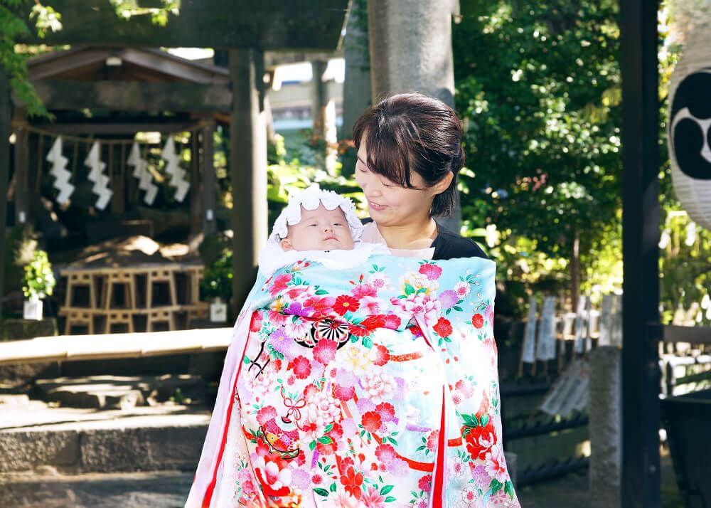 素盞嗚神社|お宮参り・七五三・お食い初め写真 10 お宮参り出張撮影で素盞嗚(スサノオ)神社の鳥居の前で赤ちゃんを抱っこするママの写真