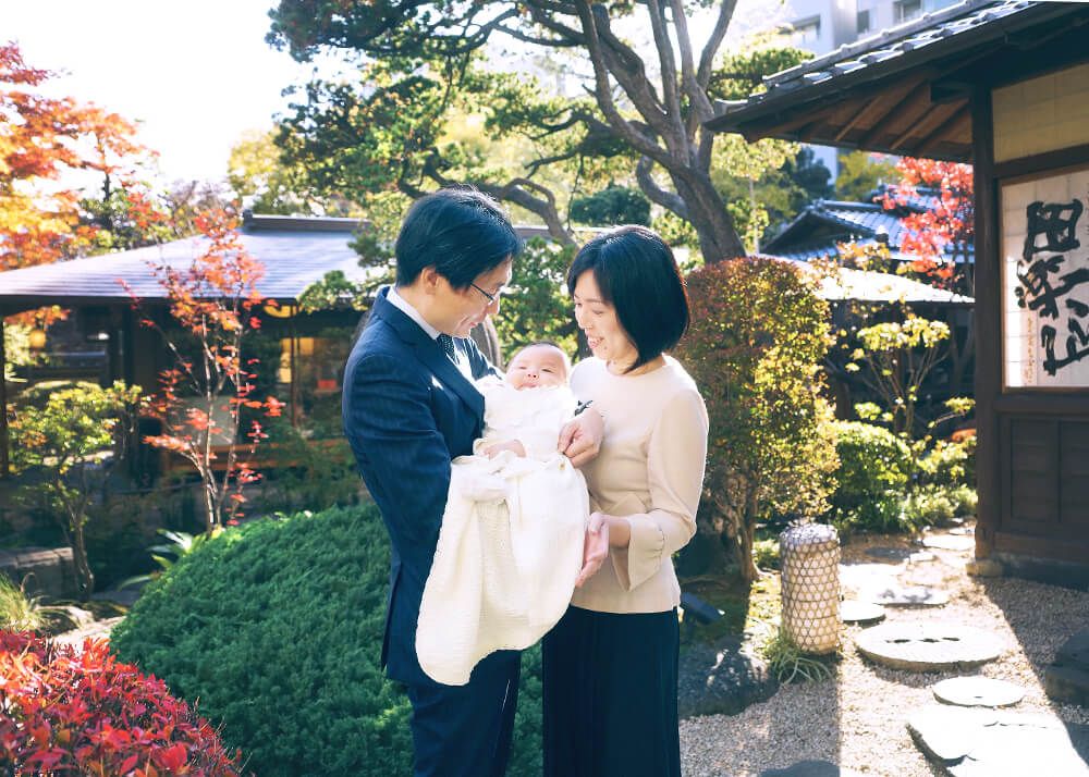 お宮参り・お食い初めロケーションフォト|赤坂日枝神社→芝とうふ屋うかい 13 芝とうふ屋うかいの庭園で赤ちゃんを囲んで撮影する家族の自然な笑顔の写真