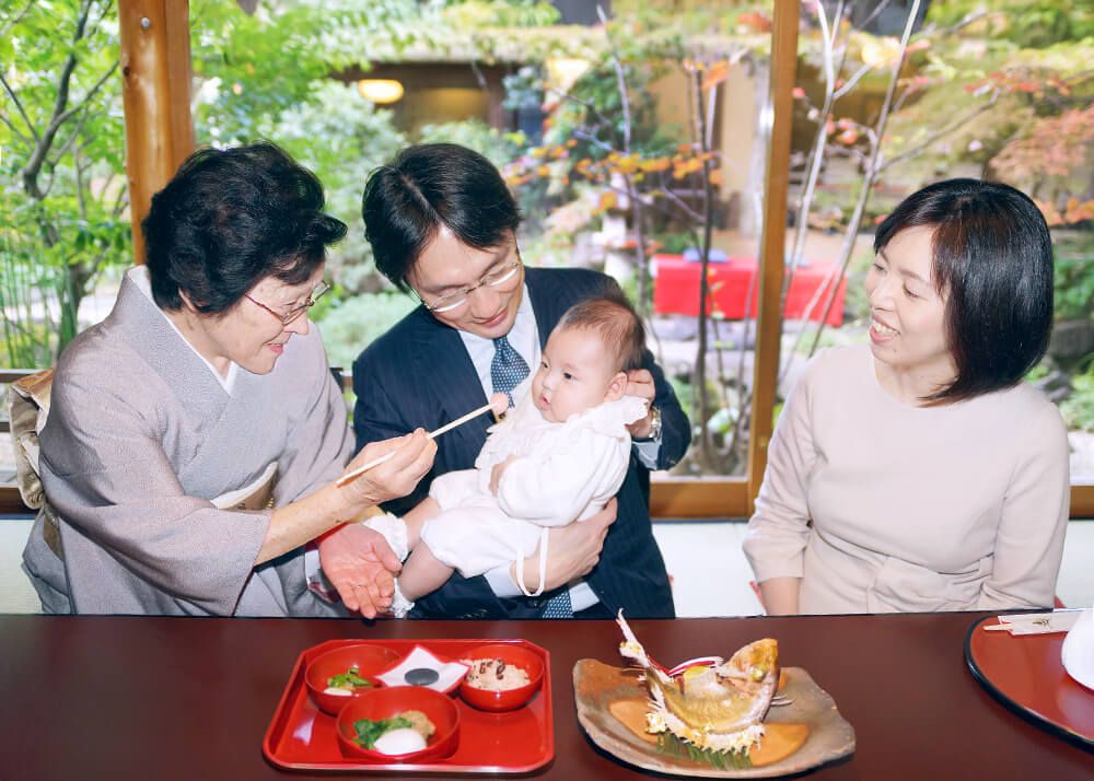 お宮参り・お食い初めロケーションフォト|赤坂日枝神社→芝とうふ屋うかい 18 お食い初めのお膳を前に微笑む家族の様子の写真|芝とうふ屋うかい出張撮影